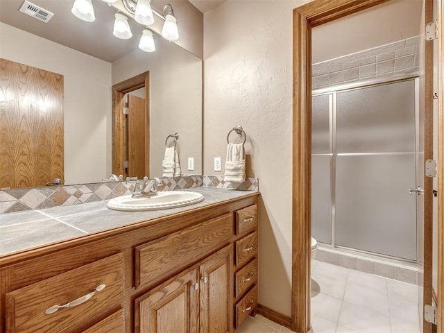 bathroom with visible vents, tile patterned flooring, a stall shower, vanity, and toilet