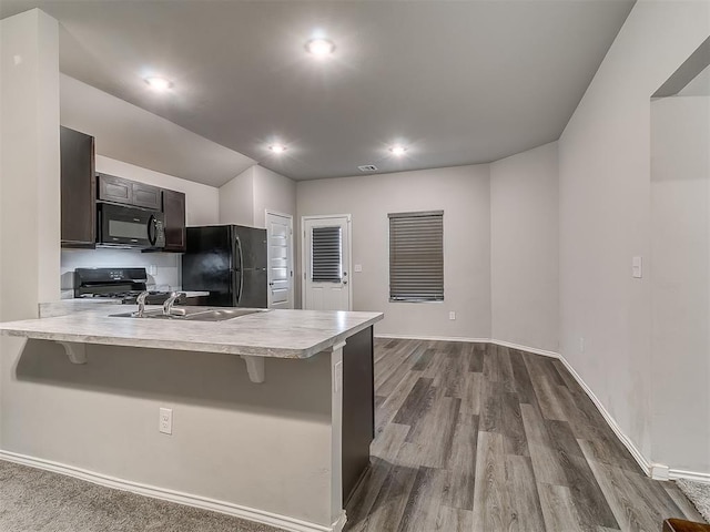 9704 Saddle Dr, Yukon, OK 73099 - kitchen featuring light countertops, black appliances, a breakfast bar, and a peninsula