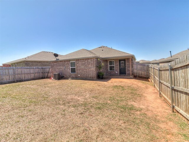 9704 Saddle Dr, Yukon, OK 73099 - rear view of house with central AC, a shingled roof, a yard, a fenced backyard, and brick siding