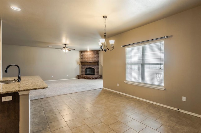 5800 SE 142nd St, Oklahoma City, OK 73165 - unfurnished living room featuring baseboards, a fireplace, carpet flooring, ceiling fan with notable chandelier, and a sink