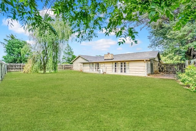 back of house featuring a fenced backyard, a lawn, and a chimney