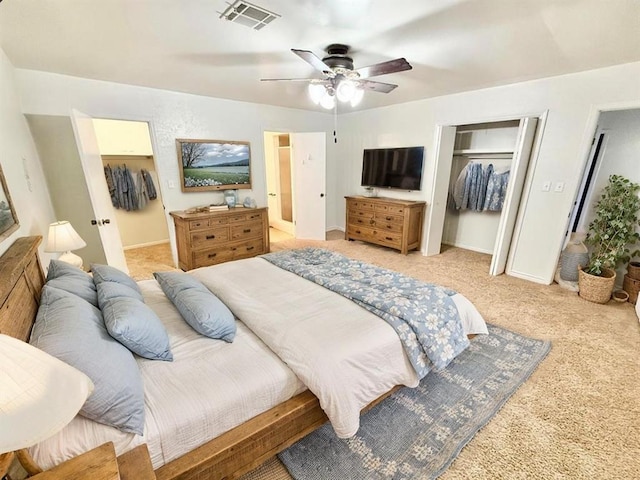 bedroom featuring ceiling fan, a closet, a spacious closet, visible vents, and light carpet