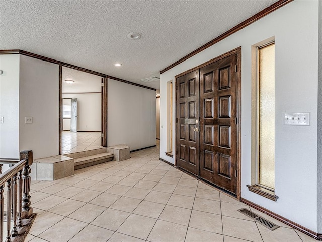 7700 S Country Club Dr, Oklahoma City, OK 73159 - entryway with ornamental molding, a textured ceiling, visible vents, and light tile patterned floors