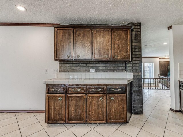 7700 S Country Club Dr, Oklahoma City, OK 73159 - kitchen with dark brown cabinets, a textured ceiling, and tile countertops