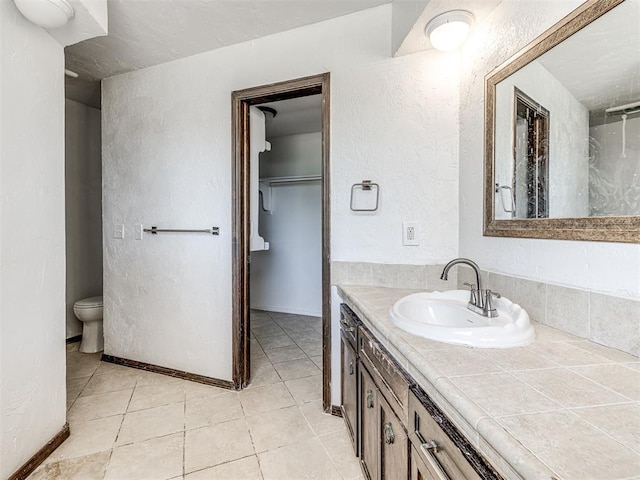7700 S Country Club Dr, Oklahoma City, OK 73159 - full bathroom featuring toilet, a textured wall, vanity, and tile patterned floors
