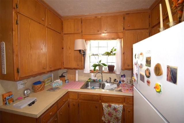 605 SW 6th St, Lindsay, OK 73052 - kitchen with a sink, brown cabinetry, light countertops, and freestanding refrigerator