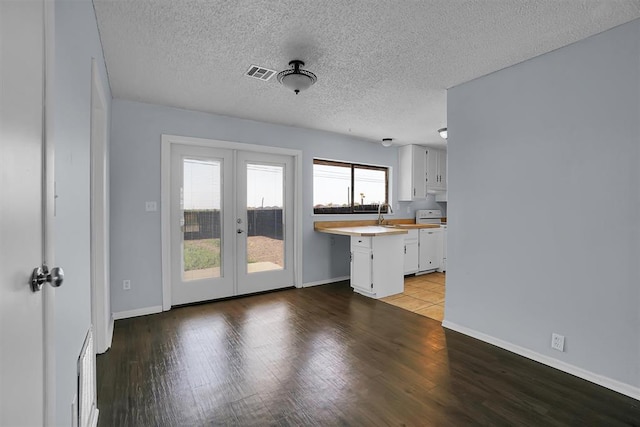 interior space featuring baseboards, french doors, a textured ceiling, visible vents, and wood finished floors