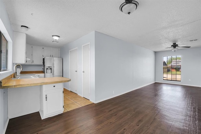 kitchen featuring stainless steel fridge with ice dispenser, a textured ceiling, a peninsula, wood finished floors, and a sink