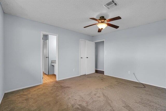 unfurnished bedroom featuring connected bathroom, a textured ceiling, visible vents, carpet flooring, and baseboards