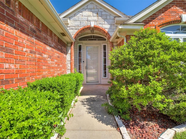 entrance to property featuring stone siding and brick siding
