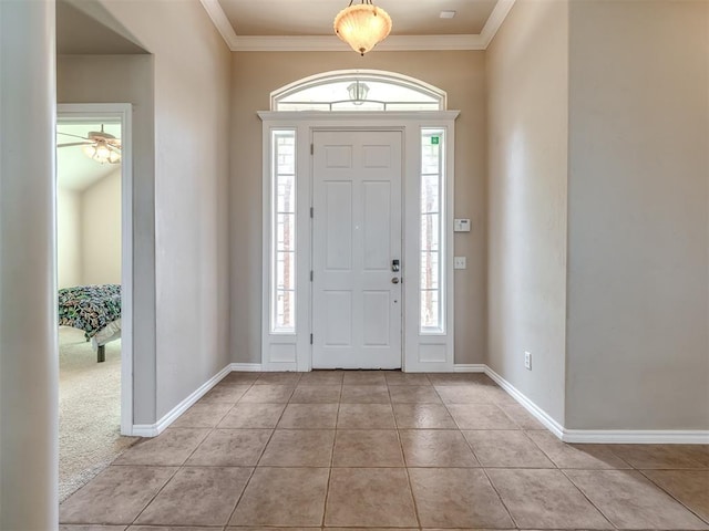 foyer with crown molding, baseboards, and tile patterned flooring