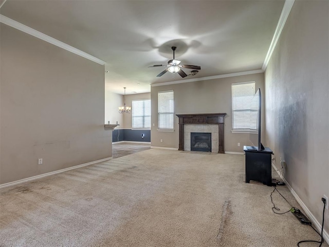 unfurnished living room with crown molding, baseboards, a tiled fireplace, carpet, and ceiling fan with notable chandelier