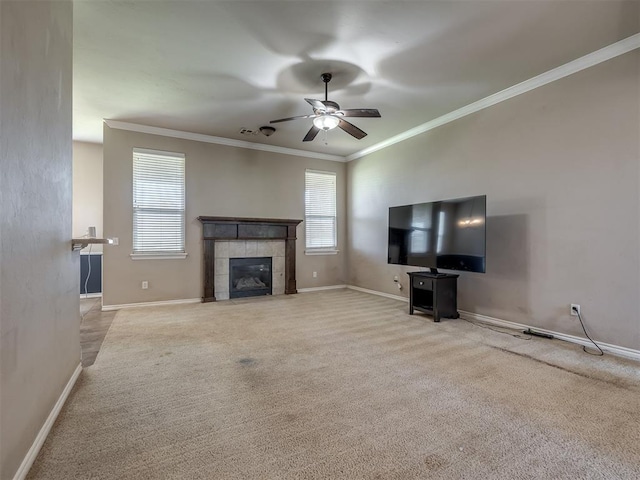 unfurnished living room with crown molding, a tiled fireplace, carpet, a ceiling fan, and baseboards
