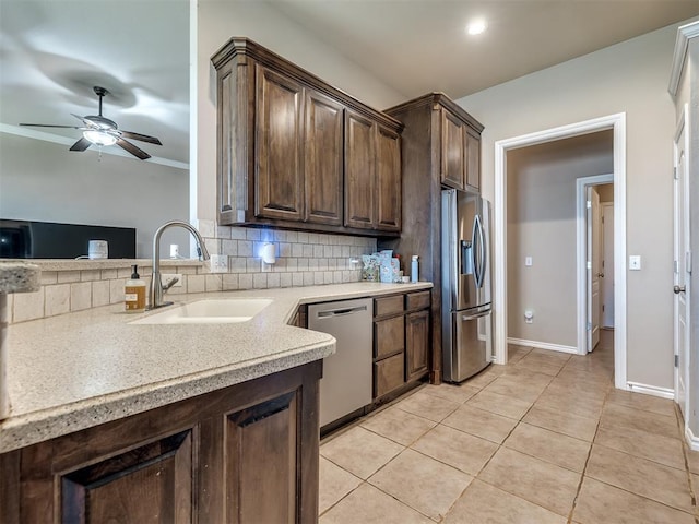 kitchen featuring ceiling fan, appliances with stainless steel finishes, dark brown cabinetry, a sink, and backsplash