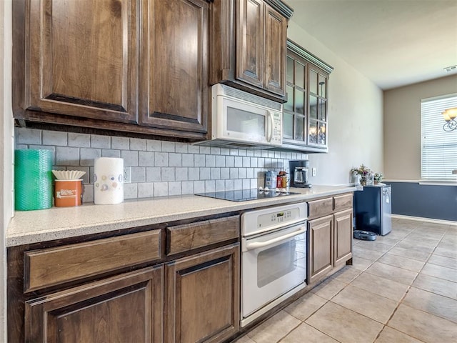 kitchen with light countertops, light tile patterned floors, decorative backsplash, and white appliances