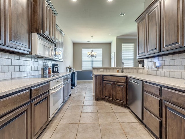 kitchen featuring a sink, decorative backsplash, a chandelier, and white appliances