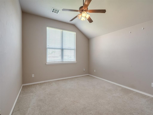 carpeted spare room with vaulted ceiling, baseboards, a ceiling fan, and visible vents