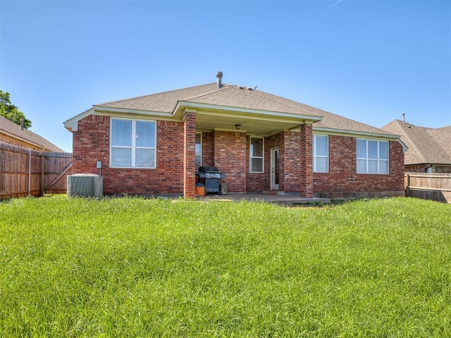 back of house featuring a fenced backyard, central AC, and brick siding