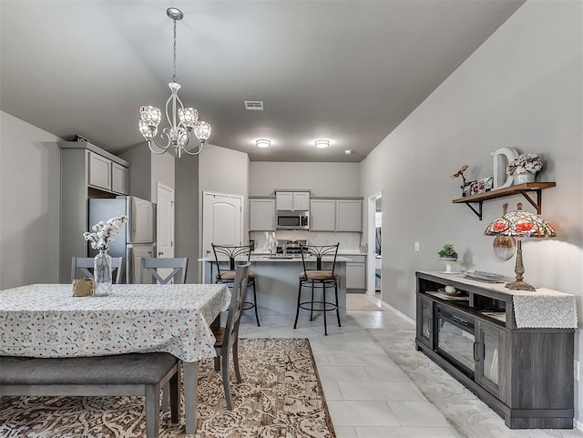 dining area with light tile patterned floors, a notable chandelier, and visible vents