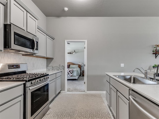 kitchen with tasteful backsplash, stainless steel appliances, light tile patterned floors, light countertops, and a sink
