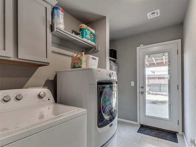 washroom featuring visible vents, light tile patterned floors, cabinet space, and washing machine and dryer