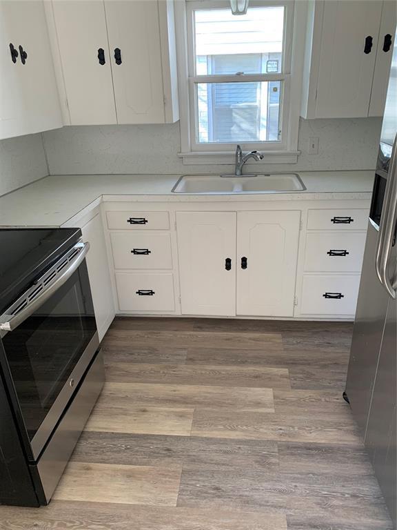1006 N Market St, Shawnee, OK 74801 - kitchen featuring stainless steel electric range oven, white cabinetry, light countertops, a sink, and fridge