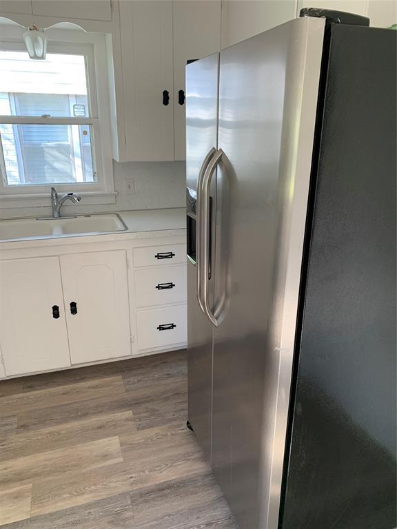 1006 N Market St, Shawnee, OK 74801 - kitchen with white cabinetry, a sink, and stainless steel fridge