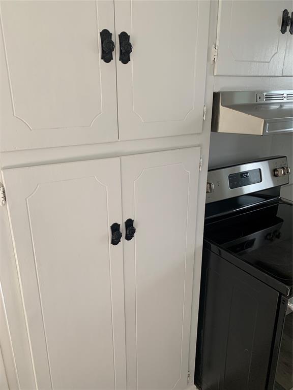 1006 N Market St, Shawnee, OK 74801 - interior details featuring white cabinets, under cabinet range hood, and stainless steel range with electric cooktop
