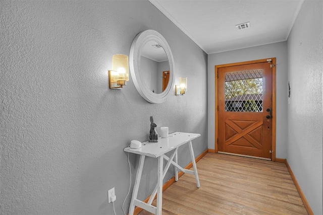 doorway to outside featuring visible vents, baseboards, light wood finished floors, and a textured wall