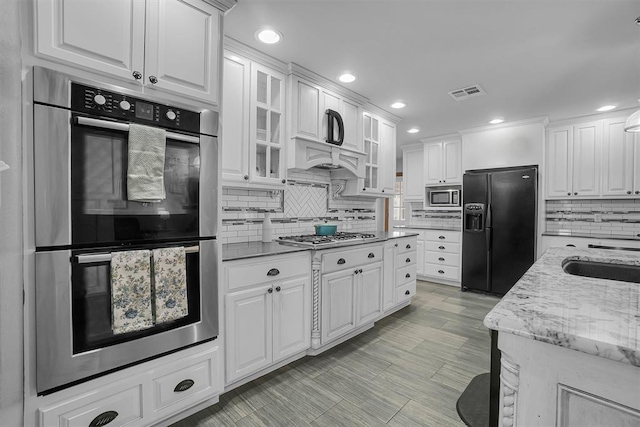 kitchen with a sink, white cabinetry, visible vents, and stainless steel appliances