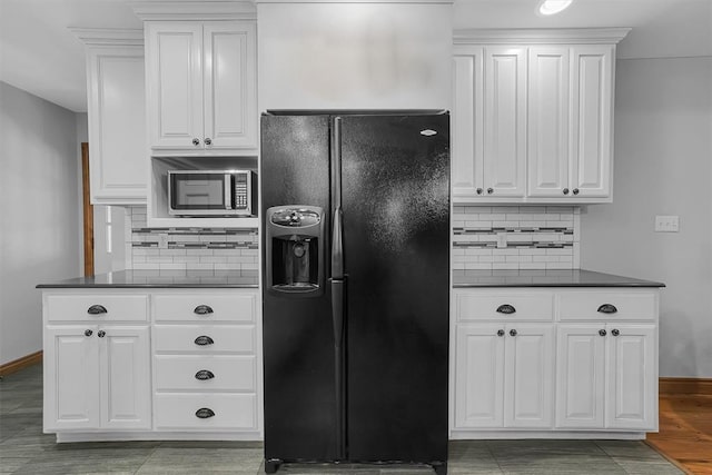 kitchen featuring black fridge, stainless steel microwave, dark countertops, and backsplash