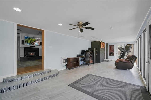 living room with a lit fireplace, baseboards, recessed lighting, heating unit, and ceiling fan