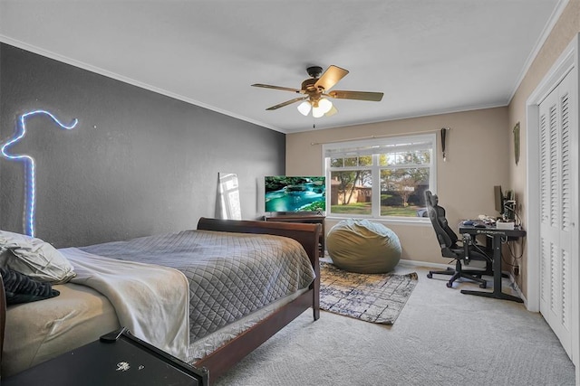 carpeted bedroom with crown molding, a closet, baseboards, and a ceiling fan
