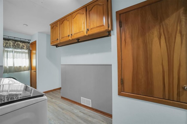 laundry area with cabinet space, visible vents, baseboards, and light wood-style floors