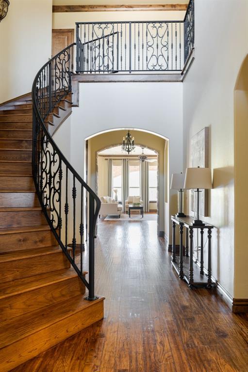 entryway featuring arched walkways, a notable chandelier, and a high ceiling