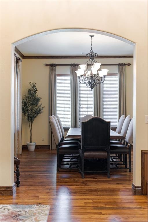 dining space with arched walkways, wood finished floors, an inviting chandelier, and baseboards