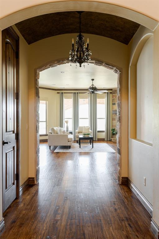 living area with dark wood-type flooring, baseboards, arched walkways, and an inviting chandelier