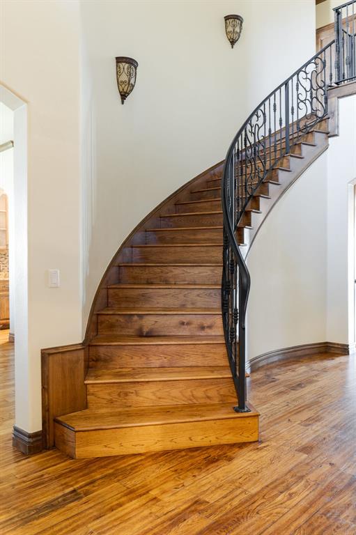 stairway featuring a high ceiling, baseboards, and wood finished floors