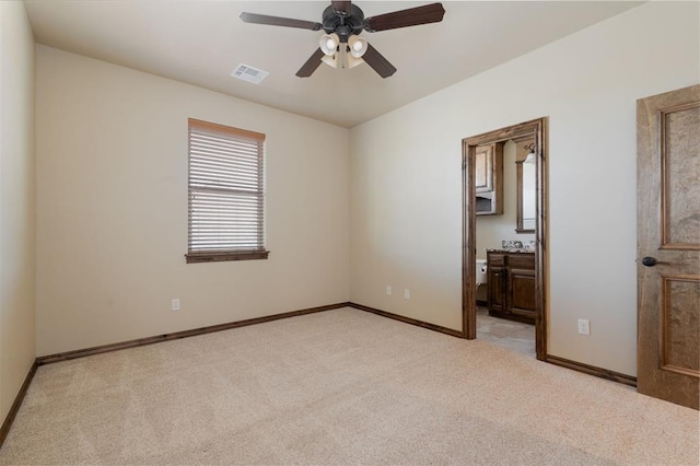 unfurnished bedroom with visible vents, baseboards, a ceiling fan, ensuite bath, and light colored carpet