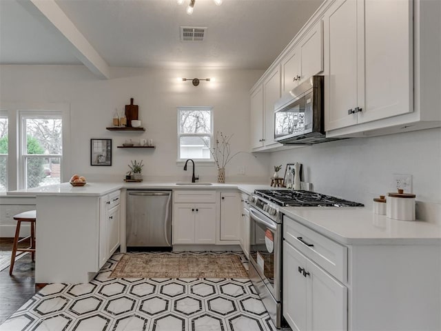 2431 NW 13th St, Oklahoma City, OK 73107 - kitchen featuring appliances with stainless steel finishes, a peninsula, a breakfast bar, and white cabinets