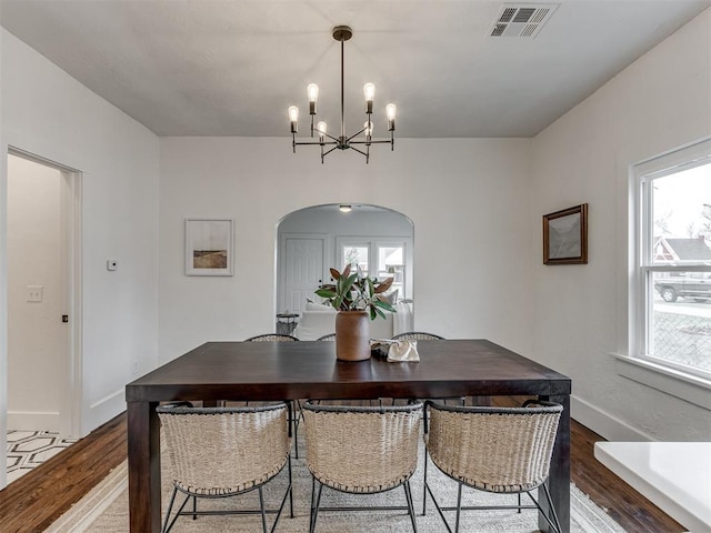 2431 NW 13th St, Oklahoma City, OK 73107 - dining room with arched walkways, a chandelier, wood finished floors, and plenty of natural light