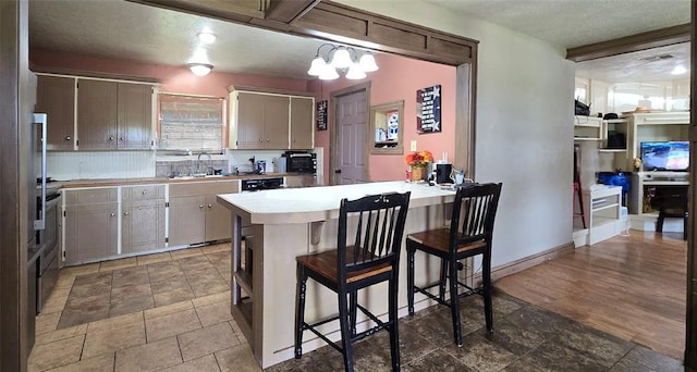 17904 Kings Rd, Shawnee, OK 74801 - kitchen featuring a peninsula, light countertops, a kitchen bar, a sink, and a chandelier
