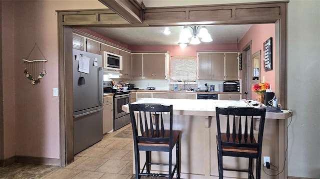 17904 Kings Rd, Shawnee, OK 74801 - kitchen featuring stainless steel appliances, a peninsula, a sink, light countertops, and a kitchen bar