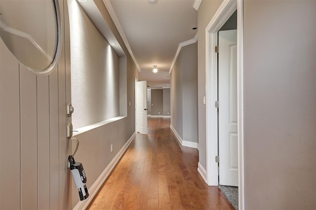 hallway featuring crown molding, baseboards, and light wood-style flooring