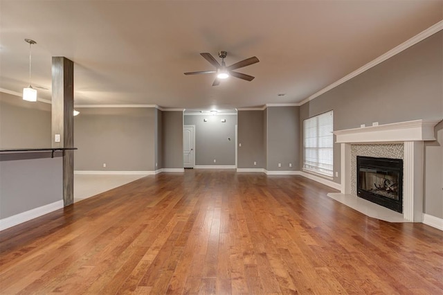 unfurnished living room featuring ceiling fan, wood finished floors, baseboards, a glass covered fireplace, and ornamental molding