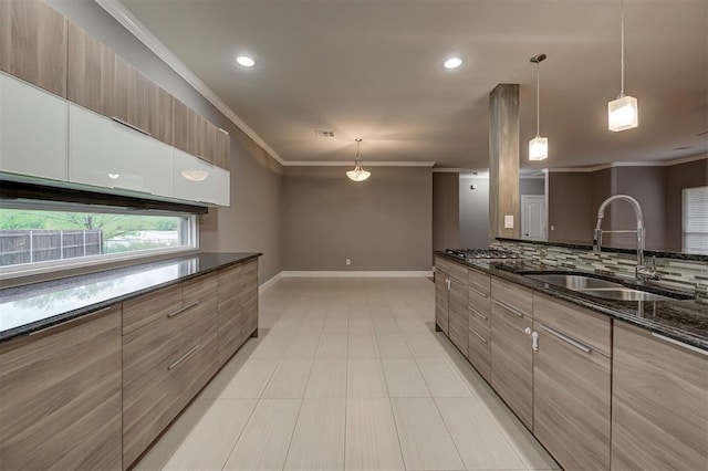 kitchen featuring a sink, dark stone counters, baseboards, decorative backsplash, and ornamental molding