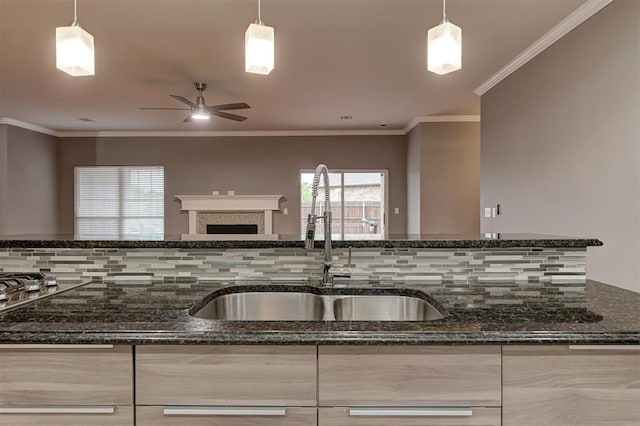 kitchen featuring ceiling fan, a sink, dark stone counters, open floor plan, and backsplash