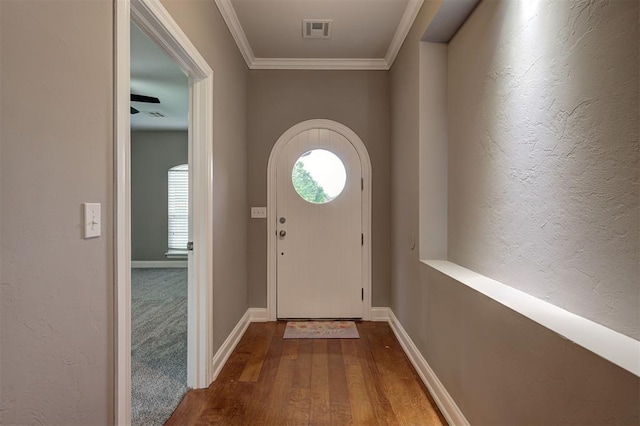 doorway featuring a wealth of natural light, ornamental molding, wood finished floors, and visible vents