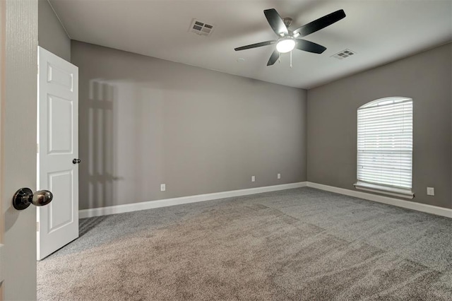 empty room featuring carpet floors, a ceiling fan, baseboards, and visible vents