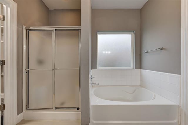 bathroom featuring a stall shower and a bath